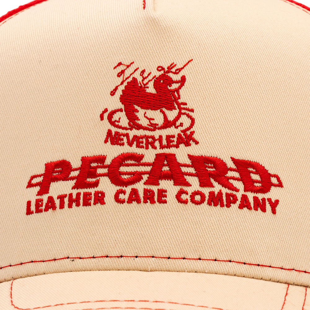 Close-up detail of the red embroidered Pecard Leather Care Company duck logo on the front of a trucker hat.